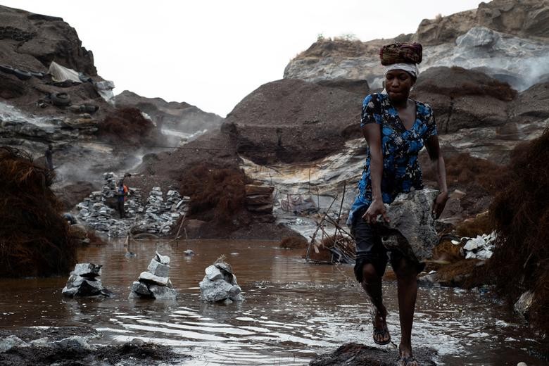 A woman carries stones out of a rain puddle at an informal granite quarry in Ouagadougou, Burkina Faso. REUTERS / Anne Mimault  